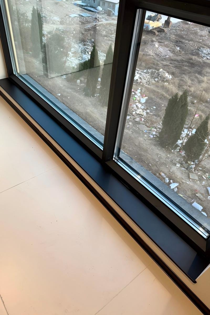 Black aluminum interior window sill and casing (NCT) installed over a light wood floor